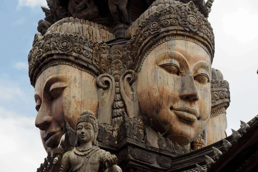 Stone sculpture showing large intricately carved faces and smaller statues at a temple site

