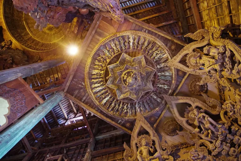 Intricate wooden ceiling carving with star-shaped centerpiece inside a traditional temple.

