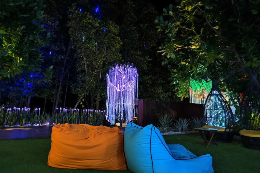 Colorful bean bags on grass with illuminated hanging light decorations in a nighttime garden setting