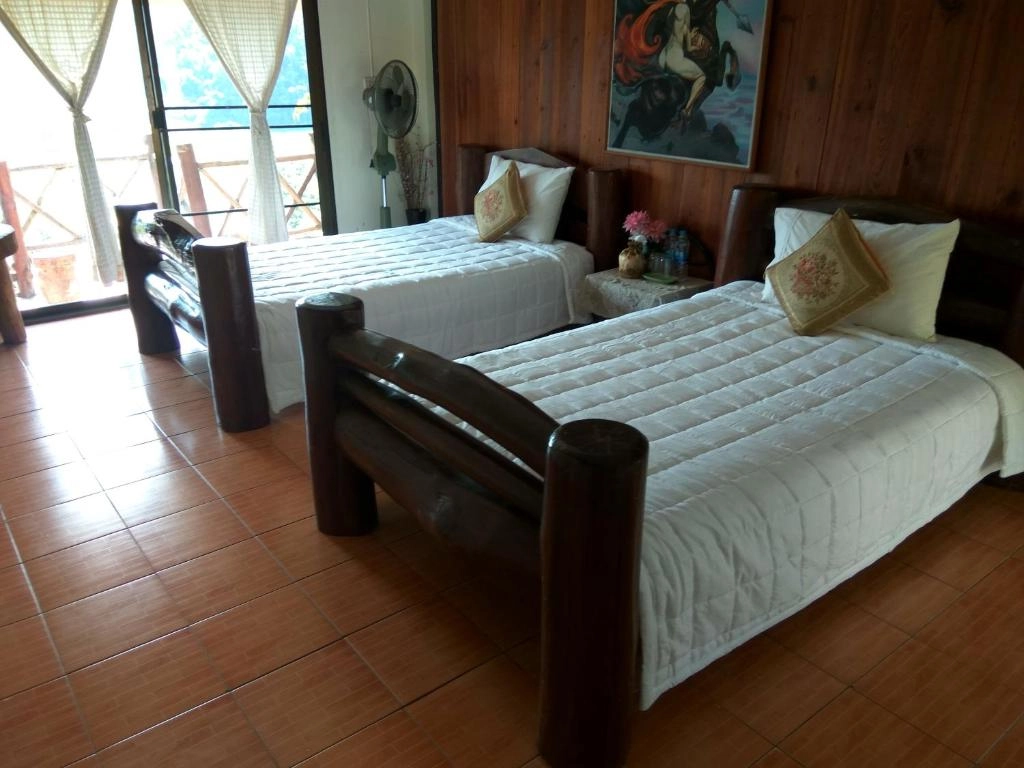 Two single beds with white quilts and pillows in a wooden cabin room with tiled floor.


