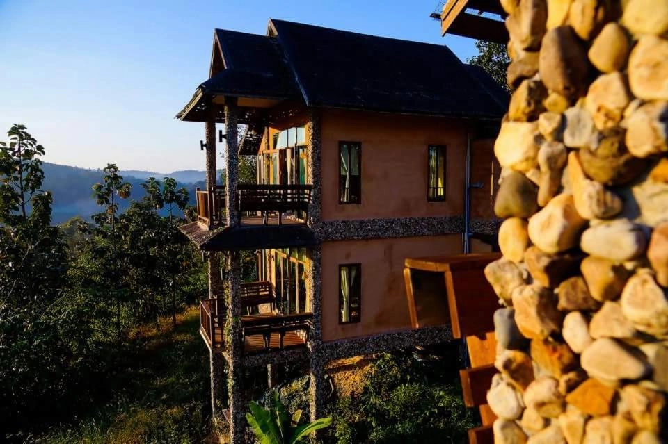 Cozy wooden mountain lodge with balconies overlooking lush green forest and hills at sunset