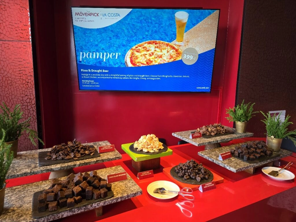 Display of assorted chocolate desserts and a digital menu showing pizza and drink offer