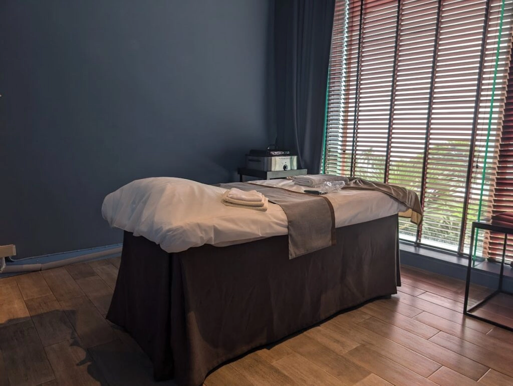 Massage table in a calm room with wooden floor and natural light through blinds