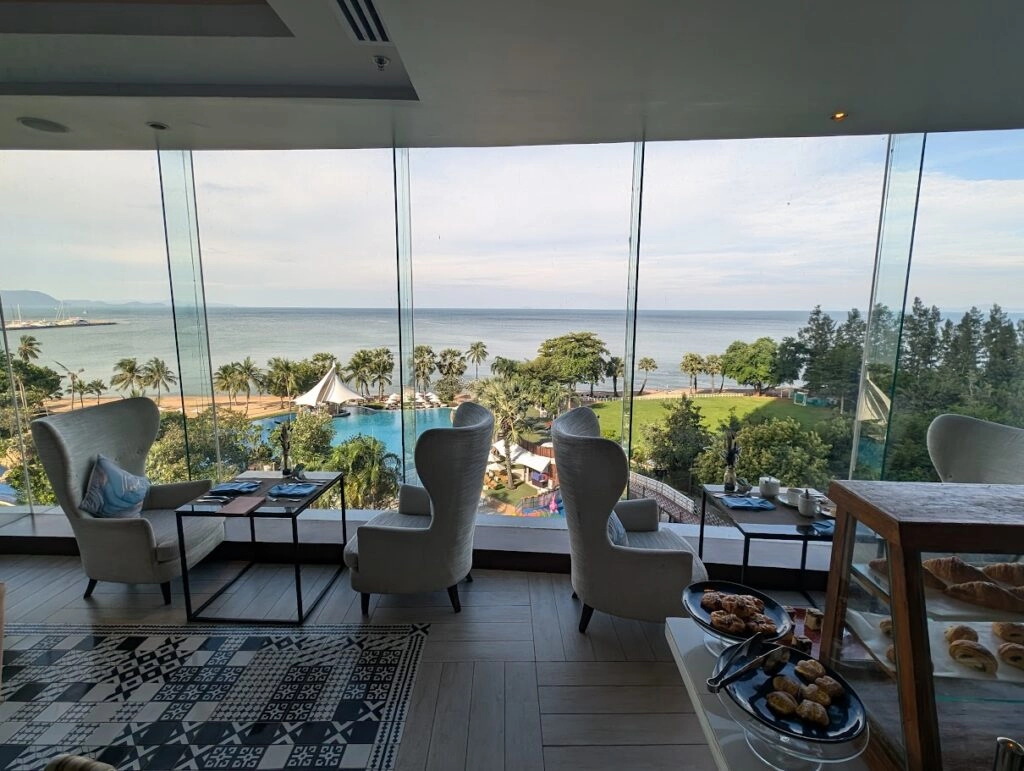 Seaside view from restaurant with chairs, tables, palm trees, and ocean horizon