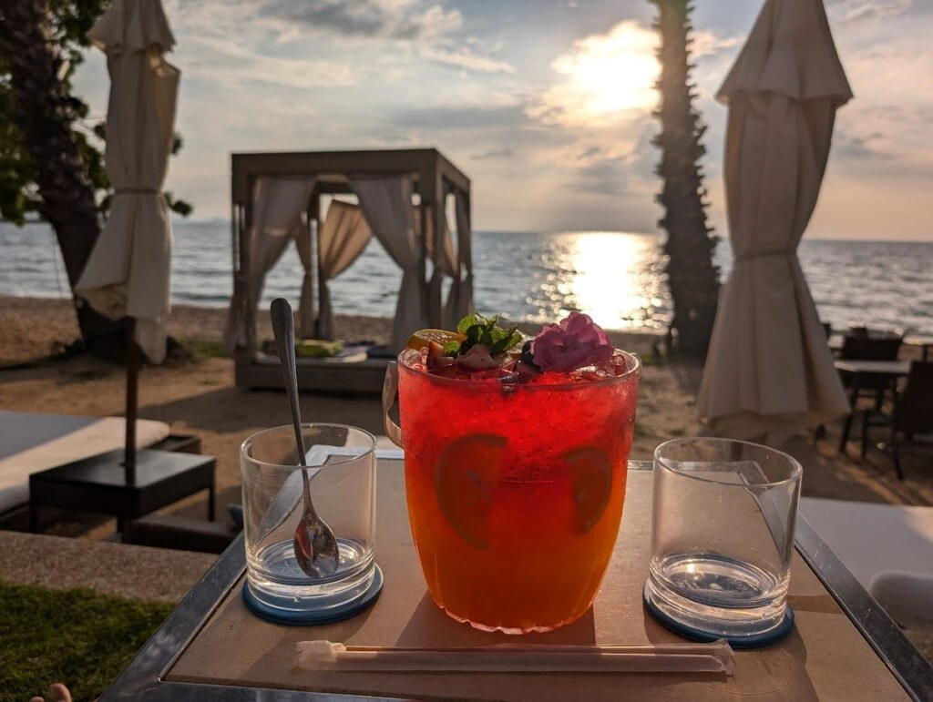 Colorful xxxl cocktail with berries on table by beachside cabana at sunset