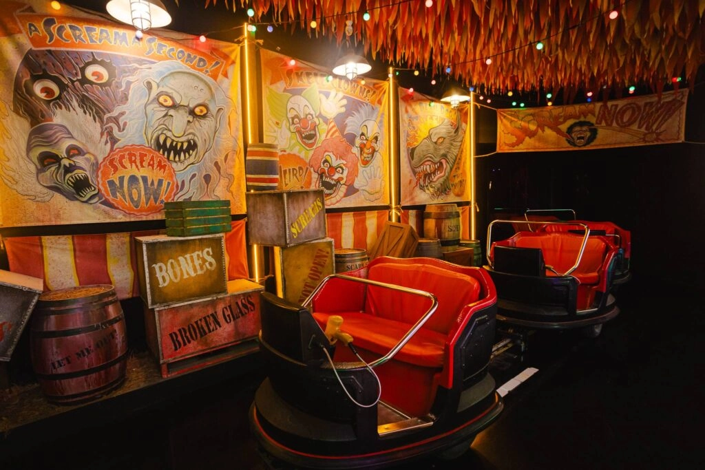 Vintage amusement park ride with red seats and spooky Halloween-themed posters on walls