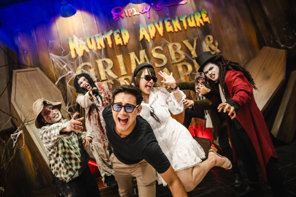 Group of friends posing excitedly with actors in spooky costumes at Grimsby Haunted Adventure.